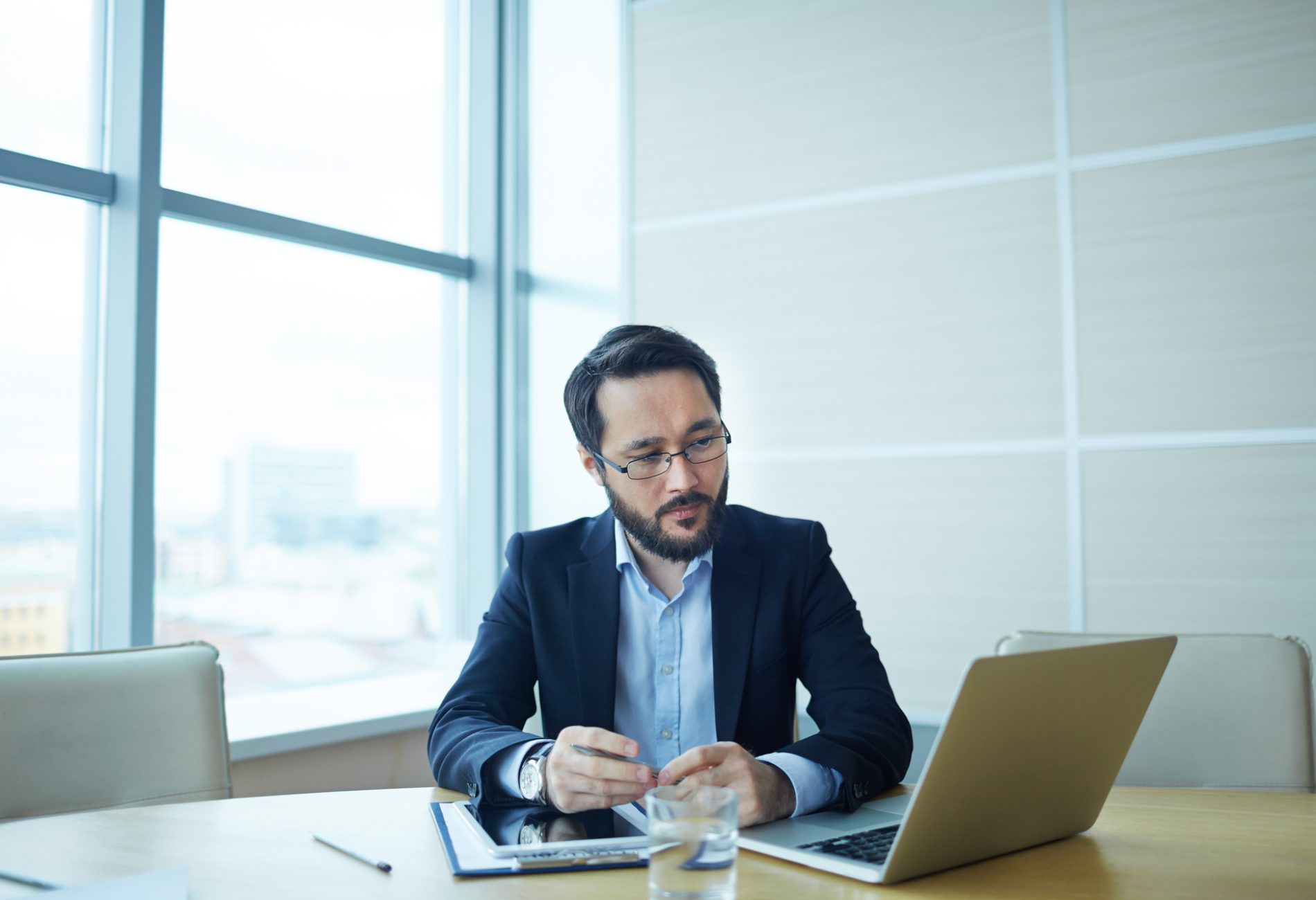 Pensive businessman looking at data in laptop at workplace